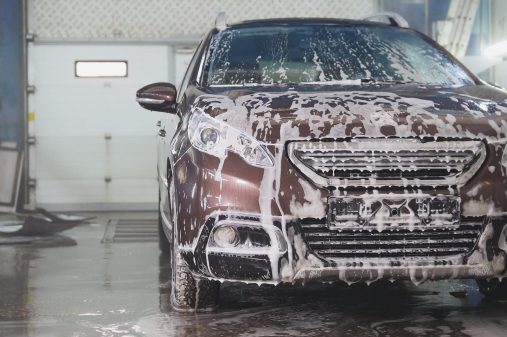 Washing a car in the suds by water hoses, wide angle